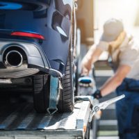 Shipping Brand New Car to Dealership Towing Truck Delivery. Shipping Modern Vehicle to Car Dealership From Auction Lot. Transportation and Cargo Theme.